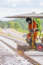 A worker works with machines on a railway track under an umbrella, grinding work on the Hermann