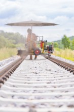 Wide-angle shot of a welder on a railway track, surrounded by nature, grinding work on the Hermann