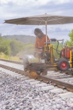 Worker welding railway track, sparks spraying, rural surroundings, grinding work on the Hermann