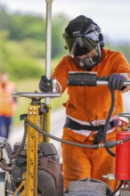 A worker in protective clothing works with heavy equipment on a railway track, grinding work on the