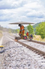 Worker working on the track with a machine under a canopy in a scenic setting, grinding work on the