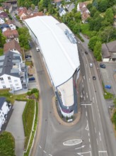 Aerial view of a modern building in an urban environment with green trees and houses, City Centre