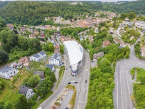 Aerial view of a modern building in a green, urban environment with nearby wooded areas, City