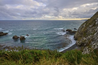 Rough sea against rocks with a cloudy sky in the background, summer, Nugget Point lighthouse,