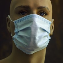 A mannequin displays a light blue surgical mask, emphasizing the significance of health safety