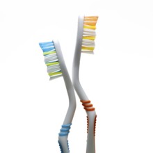 Two vibrantly colored toothbrushes stand at an angle against a plain background. They highlight the
