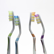 Four vibrant toothbrushes in varied colors stand side by side against a simple background,