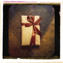 A close-up of a gift parcel elegantly wrapped in brown paper and tied with a satin ribbon, resting