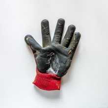 A gardening glove with a black rubber palm and a red knitted cuff is lying flat on a white surface.