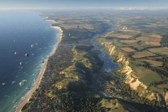 Many hot air balloons over the coast, numerous colourful balloons along a cliff at sunrise, flanked