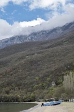 Boat on the shore of Lake Ohrid, snow-capped mountains in the background, North Macedonia