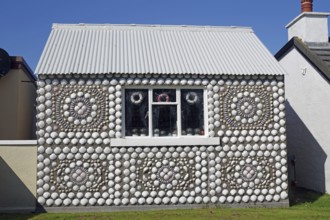 A small house with ornate shell decorations under a blue sky, Hammavoe, Shetland Islands, Scotland,