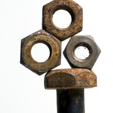 Multiple rusty nuts are stacked around a bolt, highlighting the effects of corrosion in a workshop