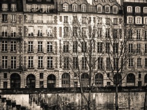 Rows of vintage buildings line the riverbank in Paris, showcasing intricate designs and tall
