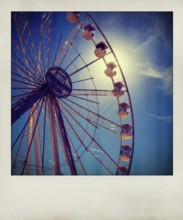 Visitors admire the towering Ferris wheel as it stands against a vibrant blue sky. The sunlight