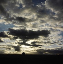 A stunning display of clouds fills the sky above rural as the sun sets, casting shadows over the