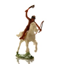A handcrafted Indian toy soldier is captured riding a white horse with a raised bow and arrow. This