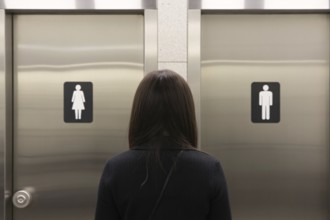 Woman in front of men's and women's bathroom doors. Concept of public restroom access and trans