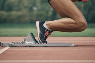 Close-up of female athlete in running shoes on starting block at running track. Concept of speed