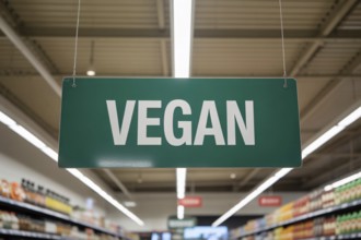 Supermarket aisle with bold green Vegan sign hanging from ceiling promoting plant-based options.