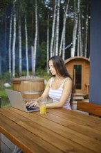 A woman finishes remote work while sitting on the terrace in the evening and is about to go to