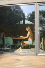 A view through the window of a woman blogger writing a post on her social network about her