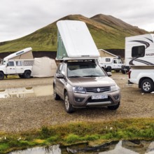 Off-road vehicle, SUV with roof tent, camping site in Landmannalaugar, Icelandic highlands, rain