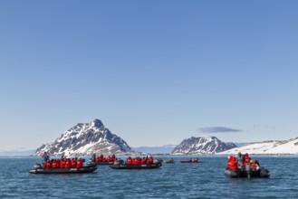 Group of Zodiacs in front of mountains with snow, sea, Fugelfjorden, Spitsbergen, Svalbard