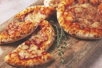 Four pizzetta Margaritas, on a cutting board, on a light gray surface, top view