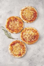 Four pizzetta Margaritas, on a light grey surface, top view