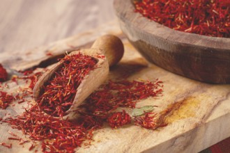 Spice saffron threads, in a wooden bowl, on a wooden table, top view, close-up