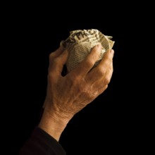 A hand gently grasps a crumpled newspaper, symbolizing the weight of information and how news is