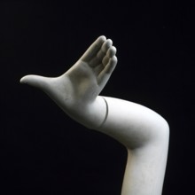 A stylized hand of a shop window dummy is elevated against a black backdrop. The sculpted hand