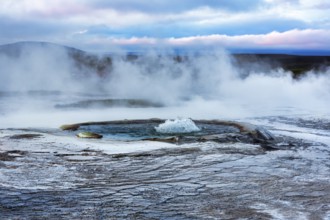 Sinter terraces with geyser, sulphur vapour, evening sky, Hveravellir geothermal area, Icelandic