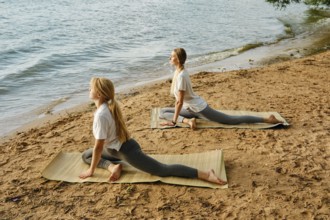 Practicing yoga poses by the serene lakeside at sunrise for relaxation and mindfulness
