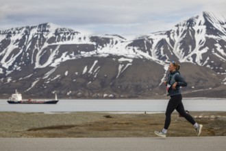 Marathon, runner in front of fjord with cargo ship, Adventtoppen, Longyearbyen, Spitsbergen,