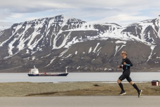 Marathon, runner in front of fjord with cargo ship, Longyearbyen, Spitsbergen, Svalbard