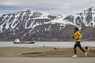 Marathon, runner in front of fjord with cargo ship, Adventtoppen, Longyearbyen, Spitsbergen,