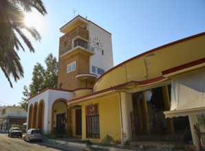Market Hall, A building with a clock tower, surrounded by palm trees, under the sun and clear sky,