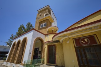 Covered market, agora, building with clock tower, characterised by red and yellow details, robust
