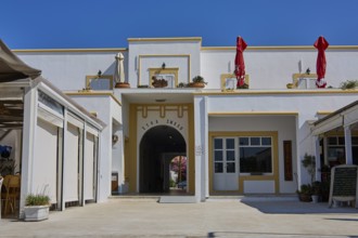 White building with entrance and decorative umbrellas on a terrace on a sunny day, Armando