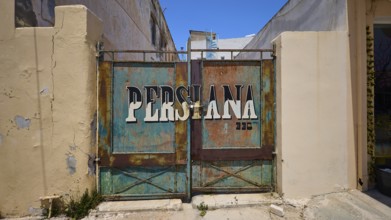 Persiana, Rusty Tor with the lettering Persiana on a dilapidated building, Armando Bernabiti,