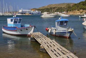 Two small boats on a jetty with a large ferry and yachts in the background, Lakki, Leros,