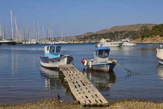 Two small boats on a wooden jetty in a quiet harbour with sailing yachts, Lakki, Leros, Dodecanese,
