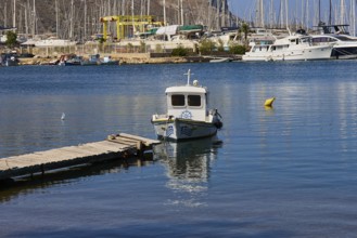 Small boat at the pier in a picturesque harbour with sailing yachts in the background, Lakki,