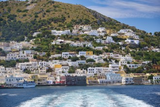 Coastal town with colourful houses on a hill, sea waves in the foreground, Lakki, Leros,