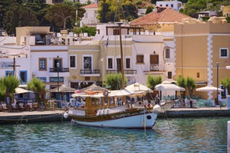 Traditional wooden boat in a lively harbour with adjoining restaurants, Lakki, Leros, Dodecanese,