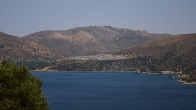 Landscape with mountains behind a blue sea under a clear blue sky, refugee shelter, Lakki, Leros,