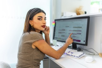 Beautician pointing at computer screen showing appointments calendar, managing schedule and
