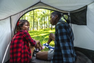 Young couple relaxing and enjoying conversation inside their tent, surrounded by the peaceful